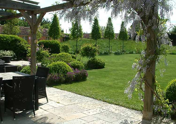 Wisteria over oak pergola hornbeam cones. Mark Langford Garden Design Berkshire
