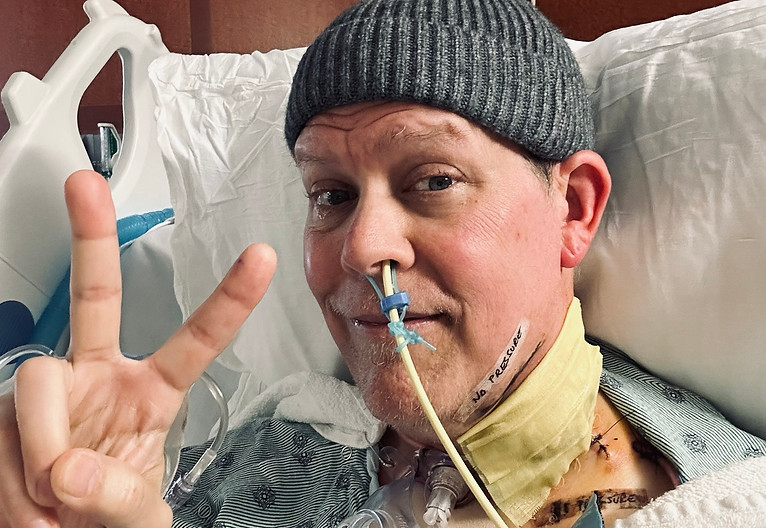 Man in hospital bed gives peace sign