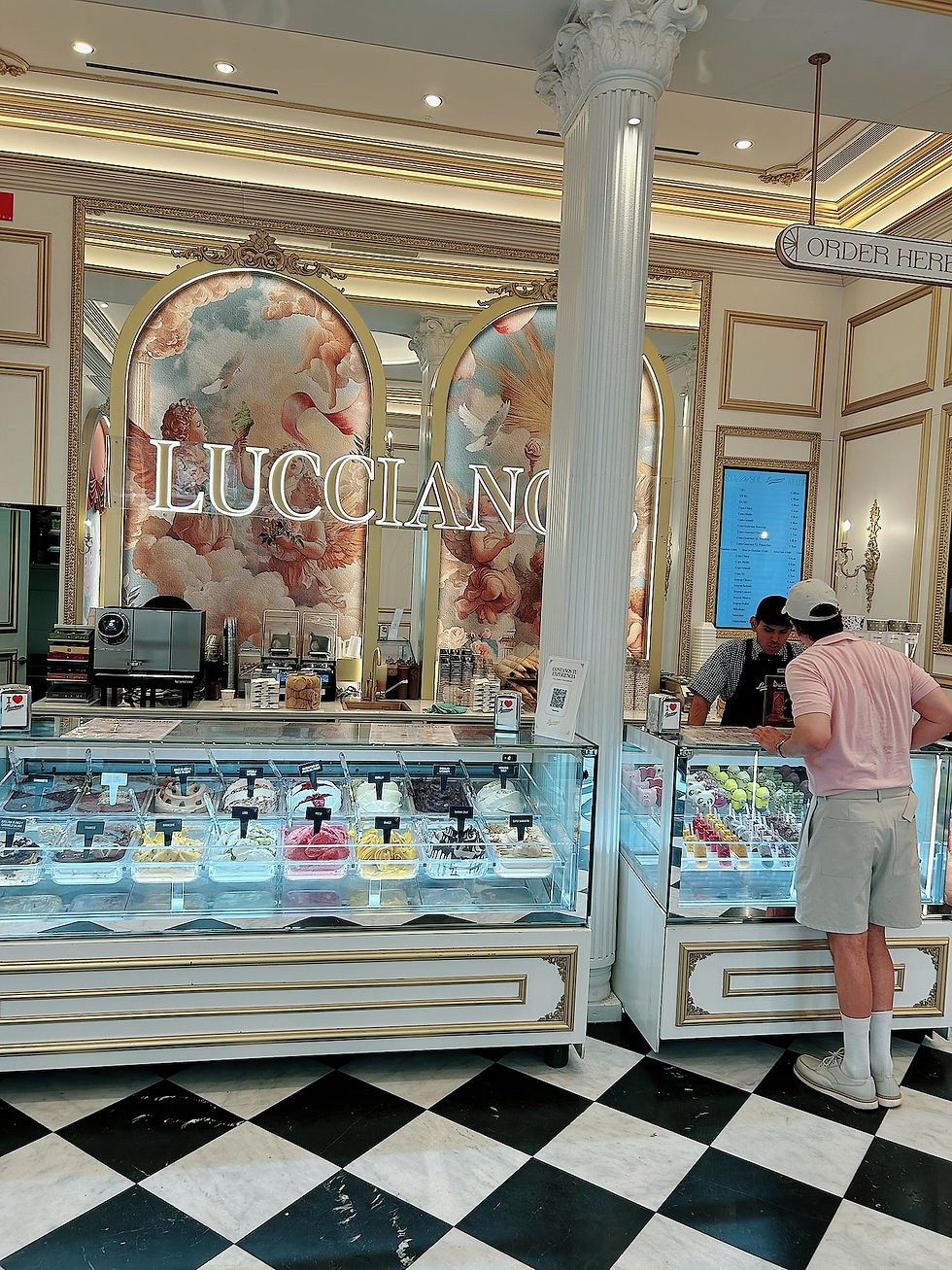 The Trendy Man pide helado en LUCCIANO, con vitrina colorida y letrero Order Here en un local elegante.