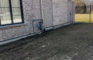 Horvath Landscaping site photo of the existing foundation edge and side yard strip with utilities next to the brick wall.