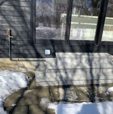 Horvath Landscaping site photo of existing back entry concrete steps and landing beside the house in winter conditions.