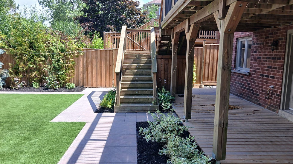 Completed backyard with fresh artificial turf, porcelain pavers, and layered plantings.