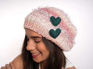 mujer con un gorrito tejido rosado, con dos broches de corzón color turquesa
