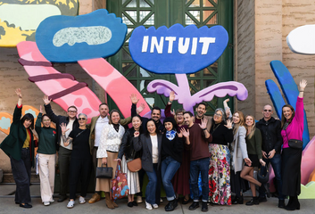 Intuit employees posing with a large floral illustrated installation outside the Palace of Fine Arts
