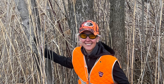 Gritty, a yellow Labrador Retriever with handler after a successful pheasant hunt, seated calmly beside a row of birds and reflecting trained retrieving ability.