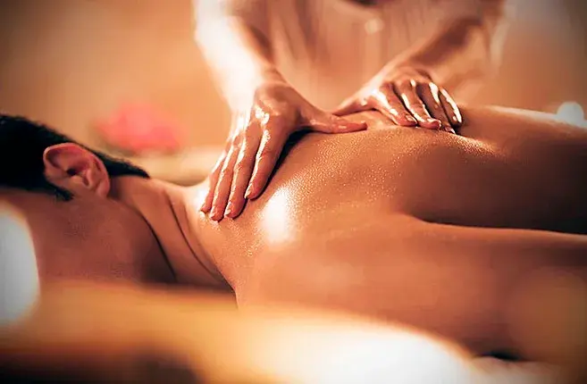 Homem deitado de bruços recebendo massagem relaxante nas costas em ambiente aconchegante, com iluminação suave e foco no alívio das tensões musculares, redução do estresse e promoção do bem-estar.