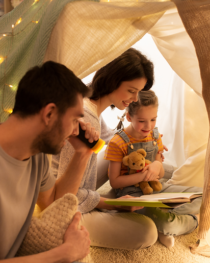 Family enjoying winter family reading time in a cozy blanket fort, sharing a story together and creating meaningful reading memories.