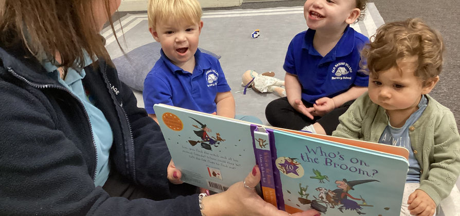 Nursery worker reading a story book to a group of young children