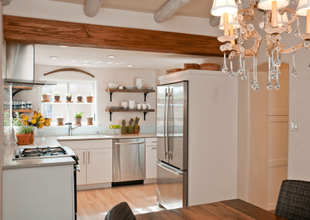 Farmhouse style kitchen with white cabinetry, floating shelves and stainless steel appliances. 