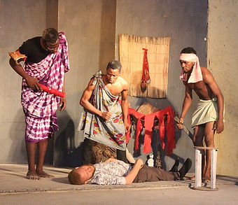 a picture from a stage play. 3 men looking down at a man who collapsed