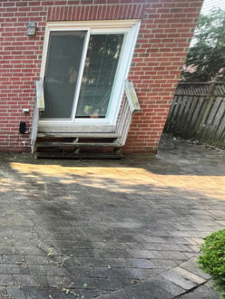 Interlock patio before lift and relevel in Oakville Ontario showing uneven pavers settling near step and improper grading