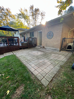 Interlock patio before re leveling in Oakville Ontario showing sloped surface edge settling and paver movement near deck
