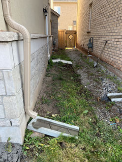 Side yard before interlock installation in Oakville Ontario showing exposed soil gravel and no walkway between homes