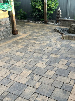Backyard patio under pergola after pressure washing showing clean multi-tone charcoal and tan interlock with restored colour