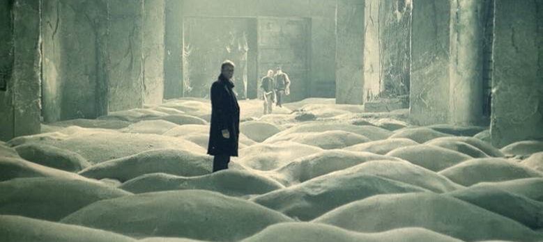 The men traverse through a sand-floored corridor in their quest to find the Room, which will supposedly make their wishes come true. Image courtesy of IMDb.com.