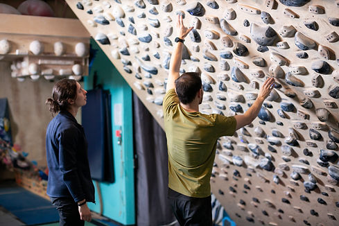 A climber and a physio are looking at the climbing wall together.