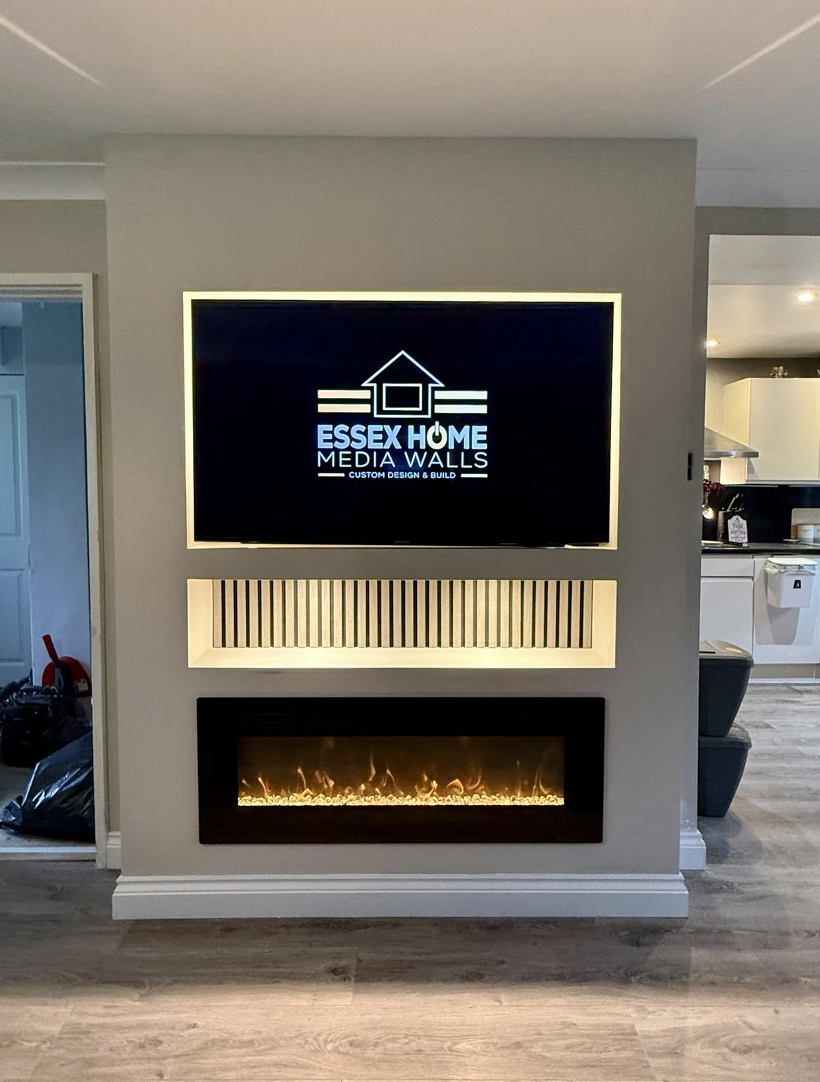 Compact media wall with a backlit TV recess and electric fire