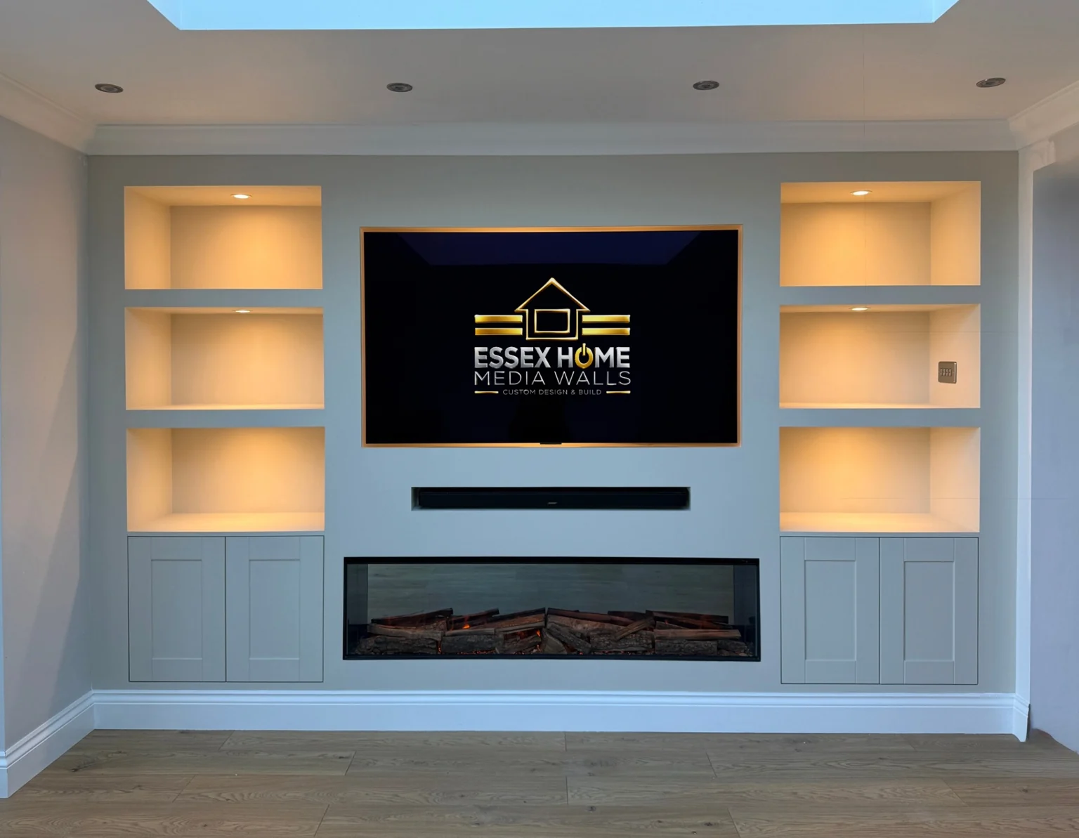 Pale media wall with warm-lit shelves and shaker-style lower cupboards
