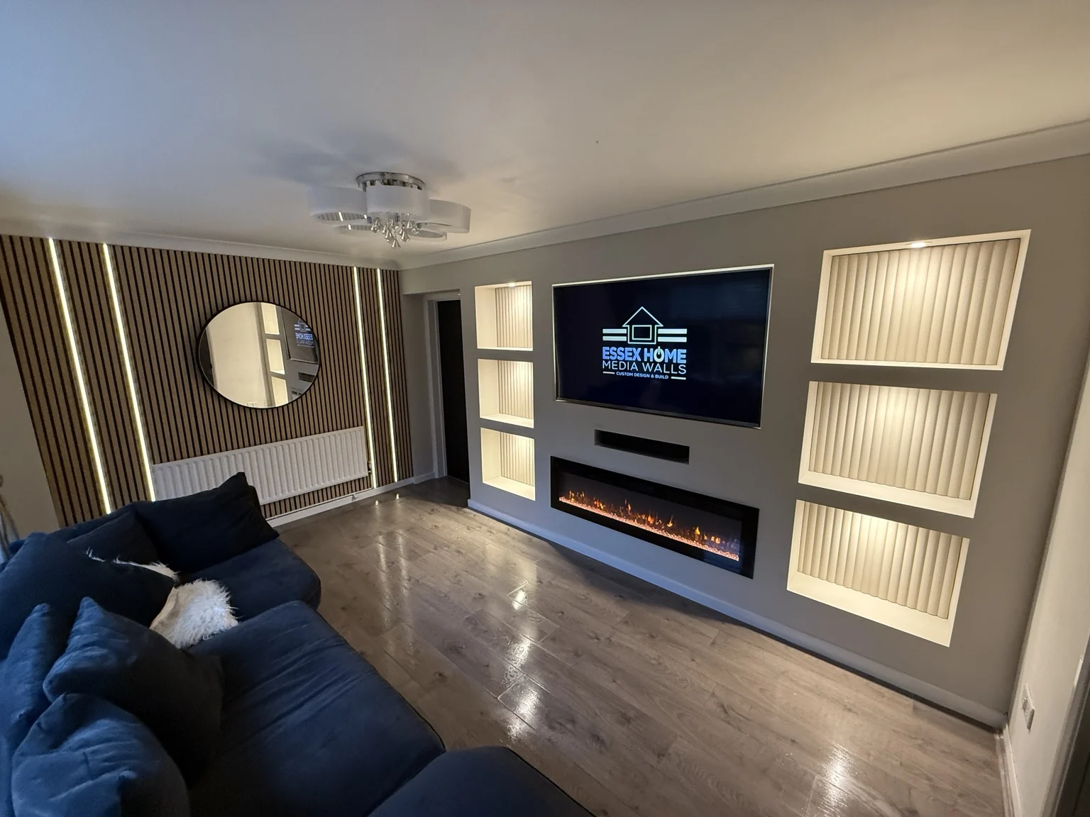 Media wall with illuminated niches beside a timber-effect panelled feature wall