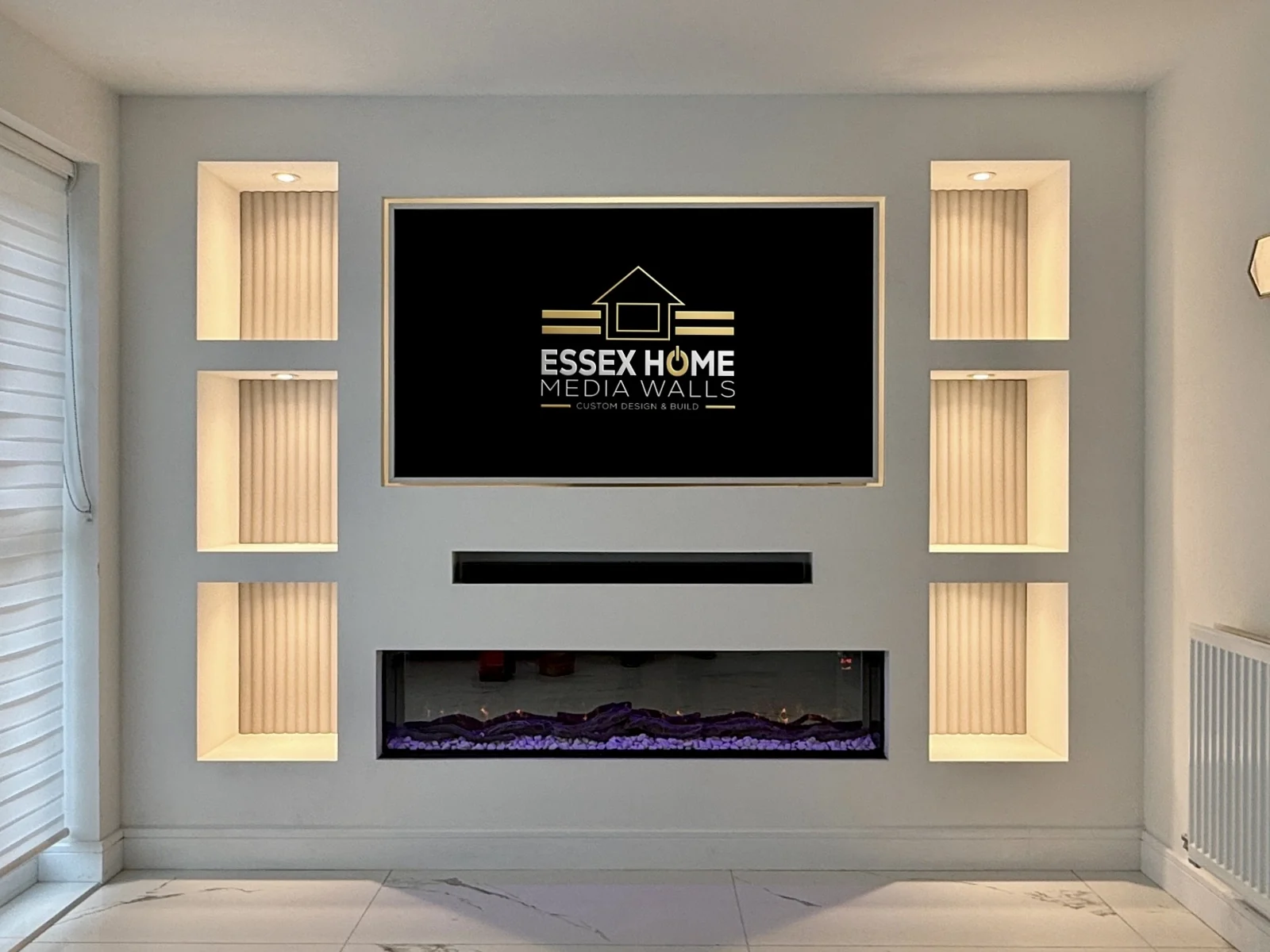 Grey media wall with six warm-lit ribbed niches and an electric fire