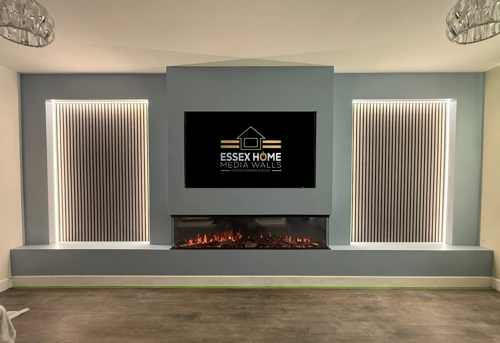 Grey media wall with illuminated fluted side panels and a low hearth
