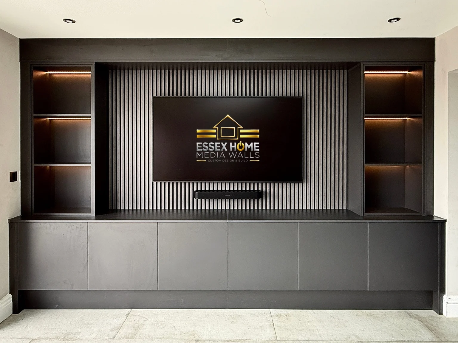 Charcoal TV wall with vertical panelling, lit shelves and full-width low cupboards