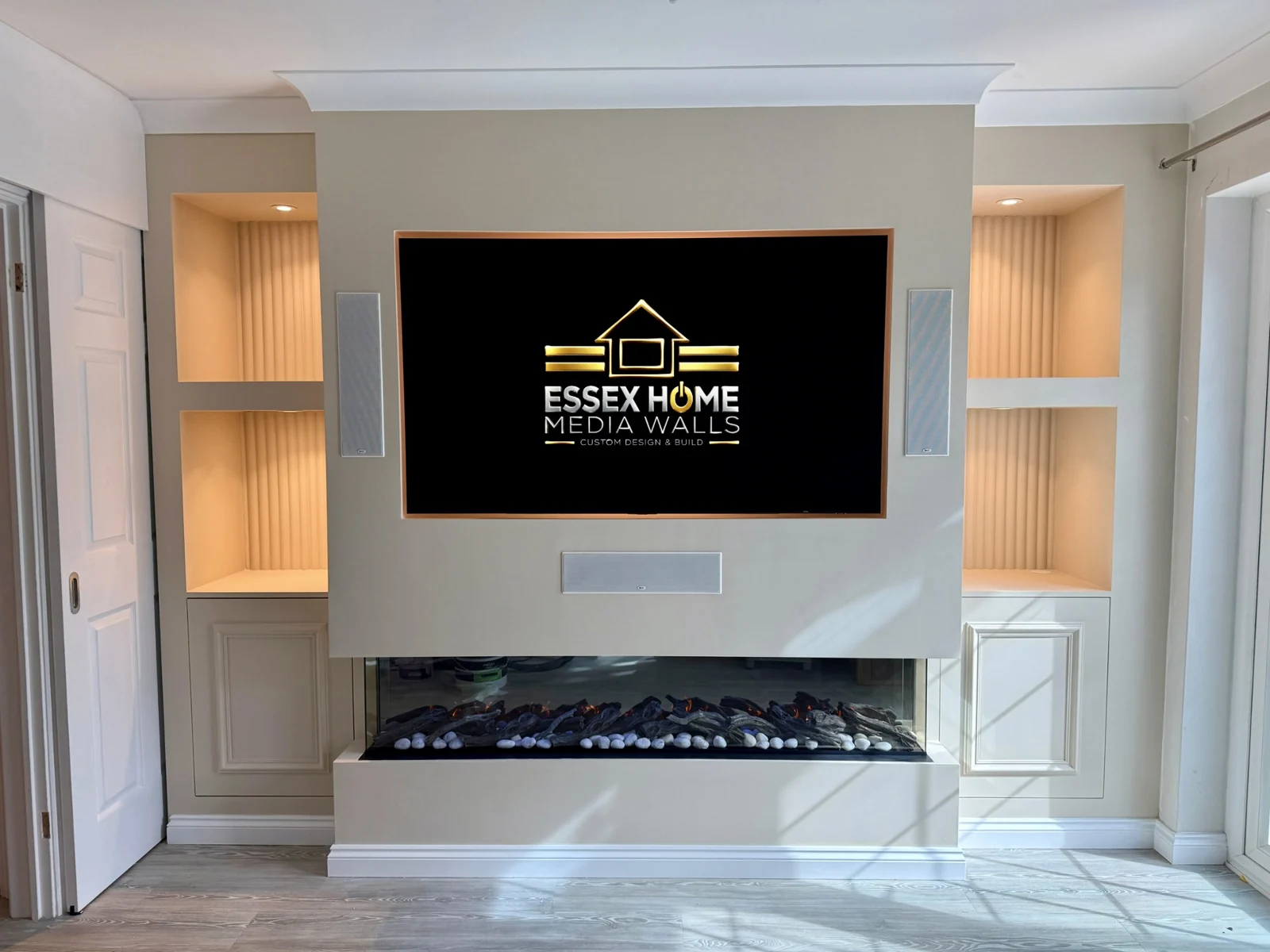 White media wall with lit side niches, lower cupboards and a wide glazed electric fire