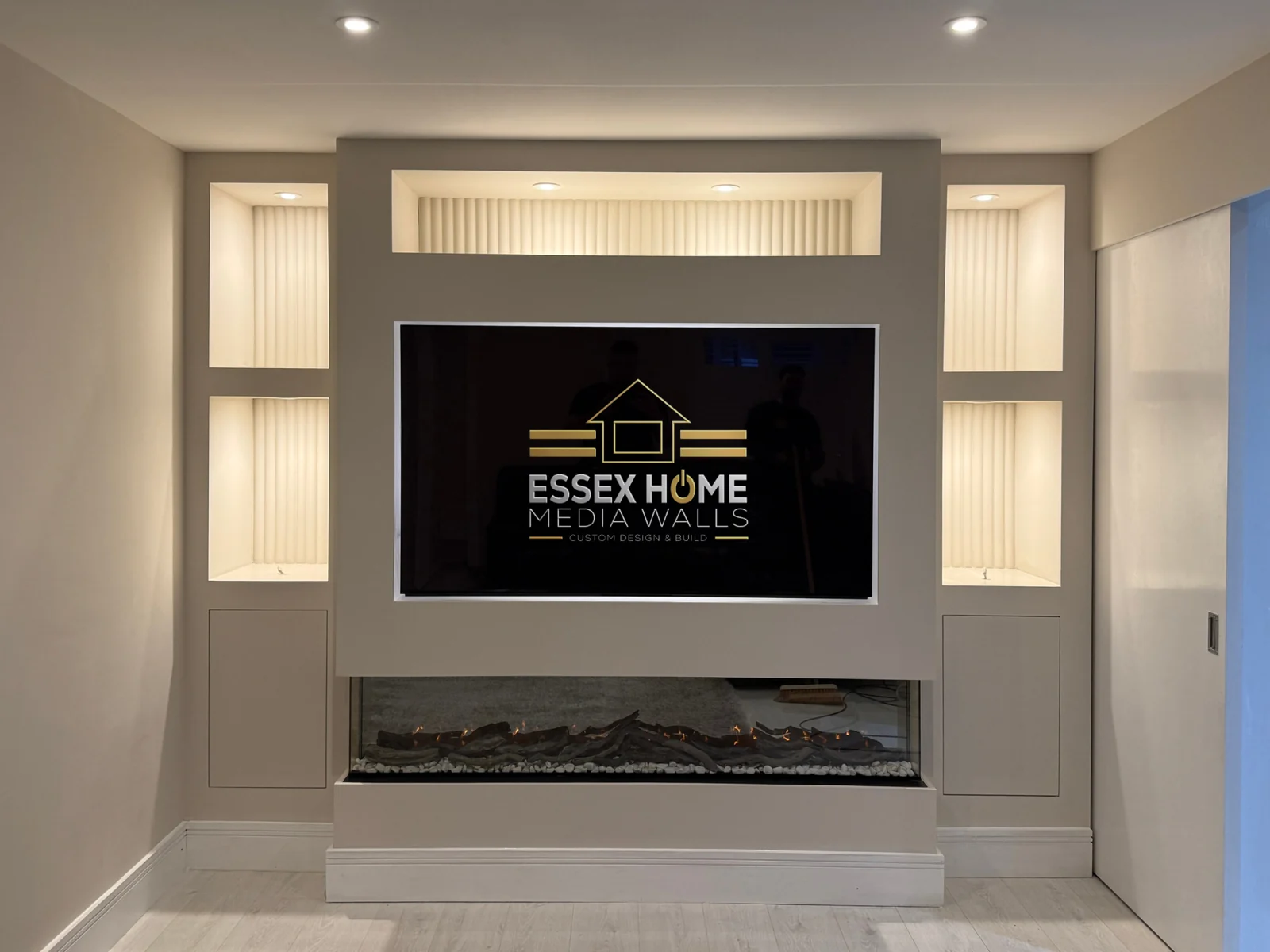 White media wall with a central TV recess, an upper display niche and lower cupboards