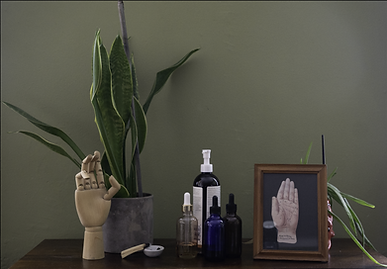 Session space details at The Loving Laboratory in Brooklyn, including massage oils, botanicals, and a wooden hand sculpture