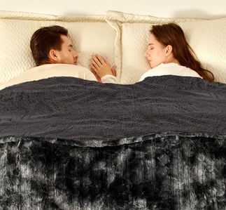 Couple sleeping soundly together, with a dark gray blanket. Peaceful bedroom scene.