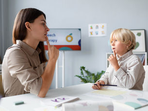 Woman doing speech therapy with a little blonde boy