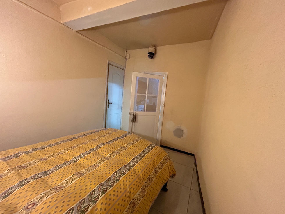 Chambre avant rénovation à Pézenas : La chambre existante, avec ses murs clairs et ses poutres peintes, avant la transformation de la maison en suite dédiée à la détente.