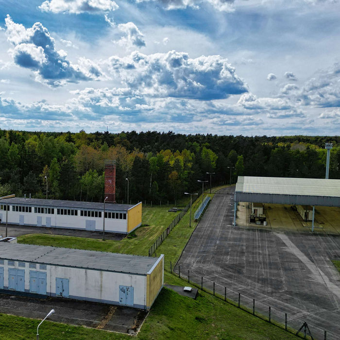 Gebäudekomplex und Wald unter einem blauen Himmel