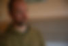 Gründer Andreas Koch, nachdenklicher Mann in grünem Hoodie, blickt zur Seite, vor hellem Hintergrund.