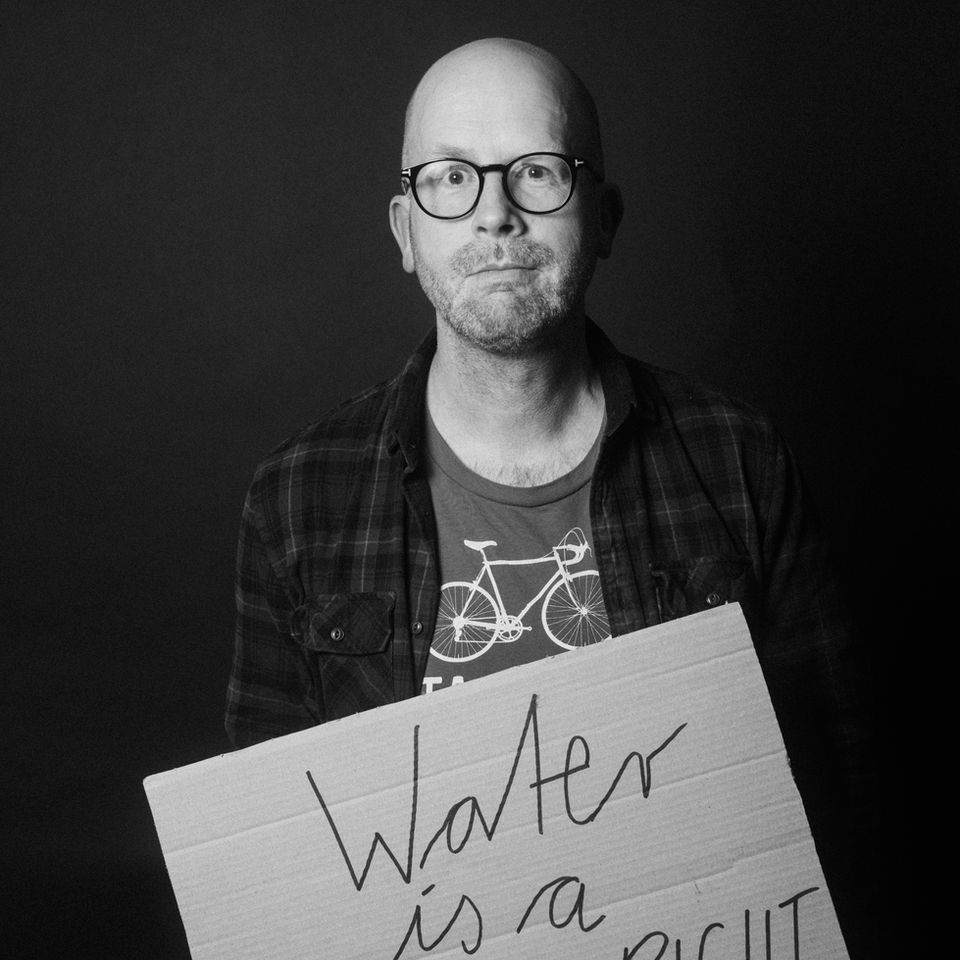 Mann hält Schild mit "Wasser ist ein Menschenrecht".
