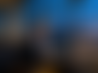 Mature woman in a dark business suit writing in a notebook while waiting at an airport gate at dusk, with a laptop beside her and an airplane visible outside large windows symbolizing end-of-year reflection across borders.