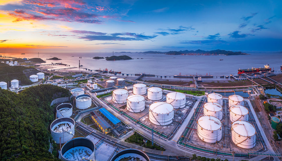 Massive coastal oil and gas terminal with white storage tanks at the port at dusk Global t