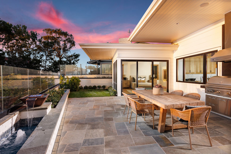 a patio with a wooden table and chairs in front of a house