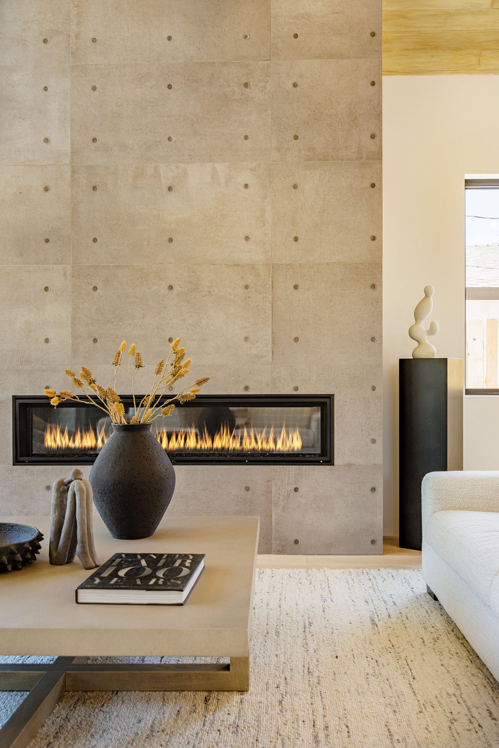 a living room with a fireplace and a vase of dried flowers