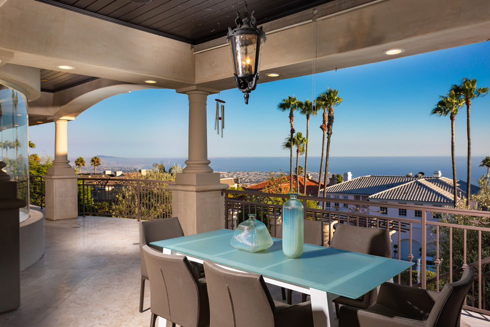 a table and chairs on a balcony overlooking the ocean