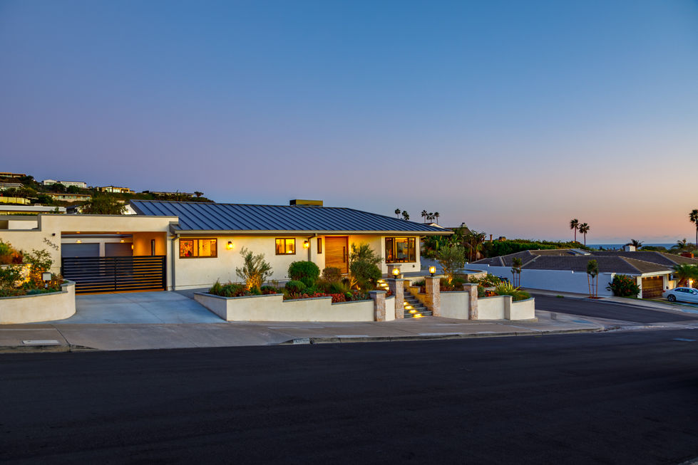 a white house with a black roof sits on a hill