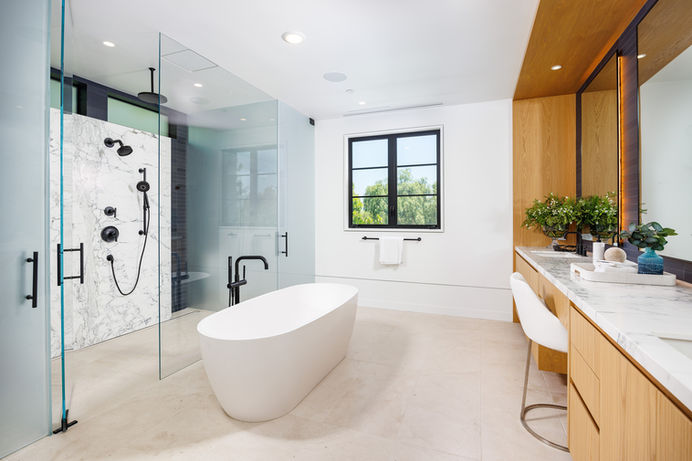 Modern master bathroom with a freestanding bathtub, glass shower stall, double sinks with marble countertops, and modern fixtures. Real estate photography by Adam Dubich Photography, Orange County, California.
