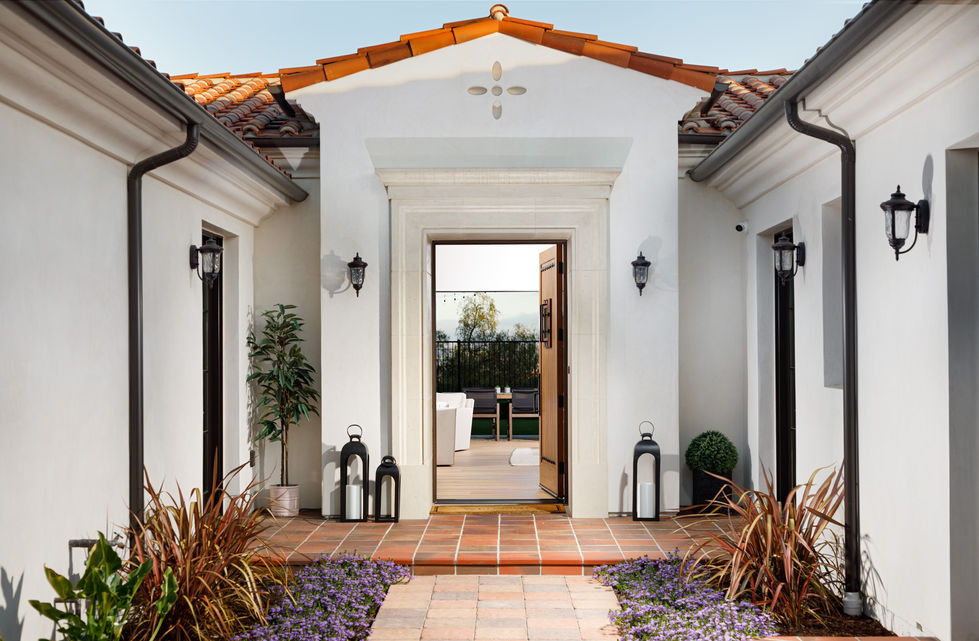 a white house with a red tile roof has a door that is open