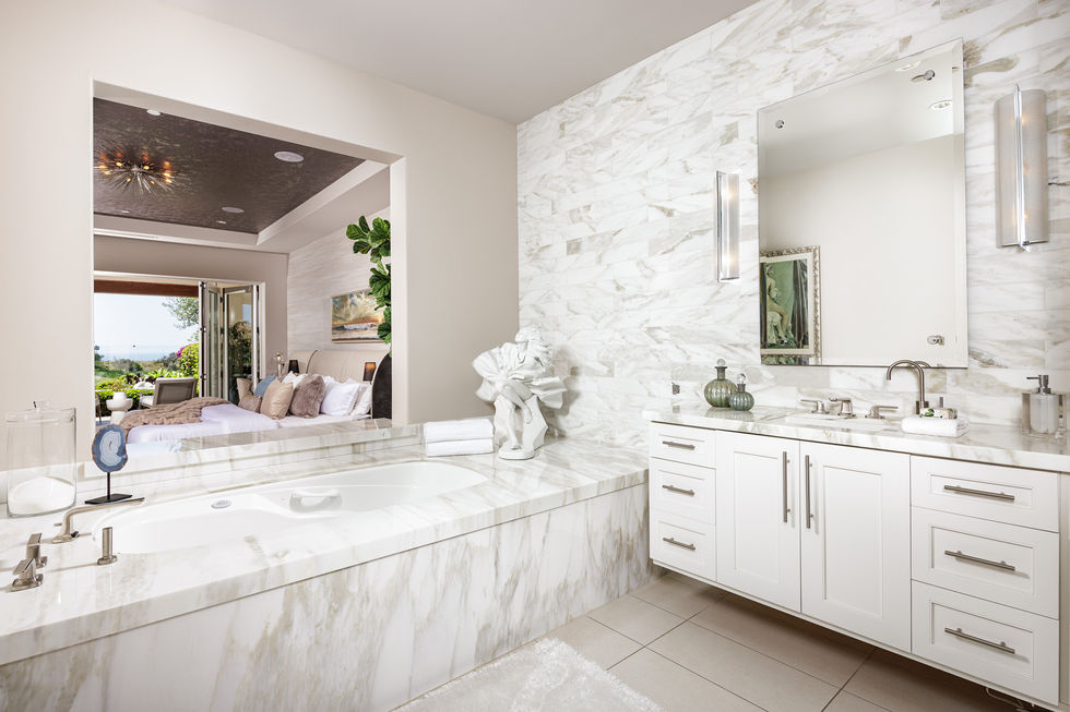 a bathroom with white cabinets and marble walls