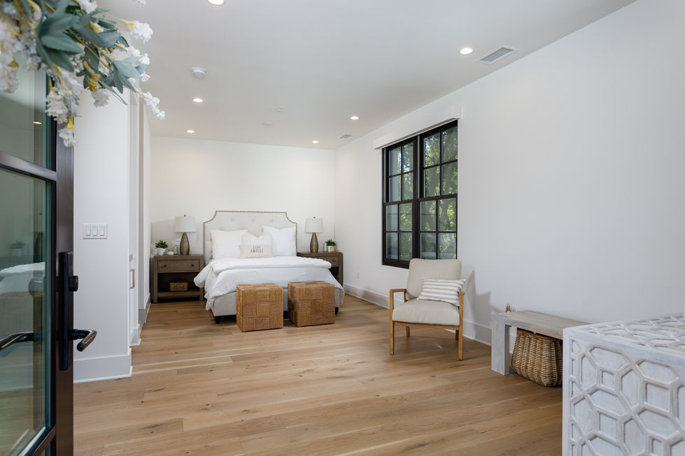a bedroom with a bed and two wicker ottomans