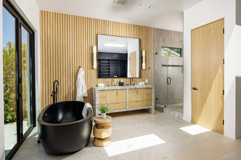 a bathroom with a black tub and a large mirror