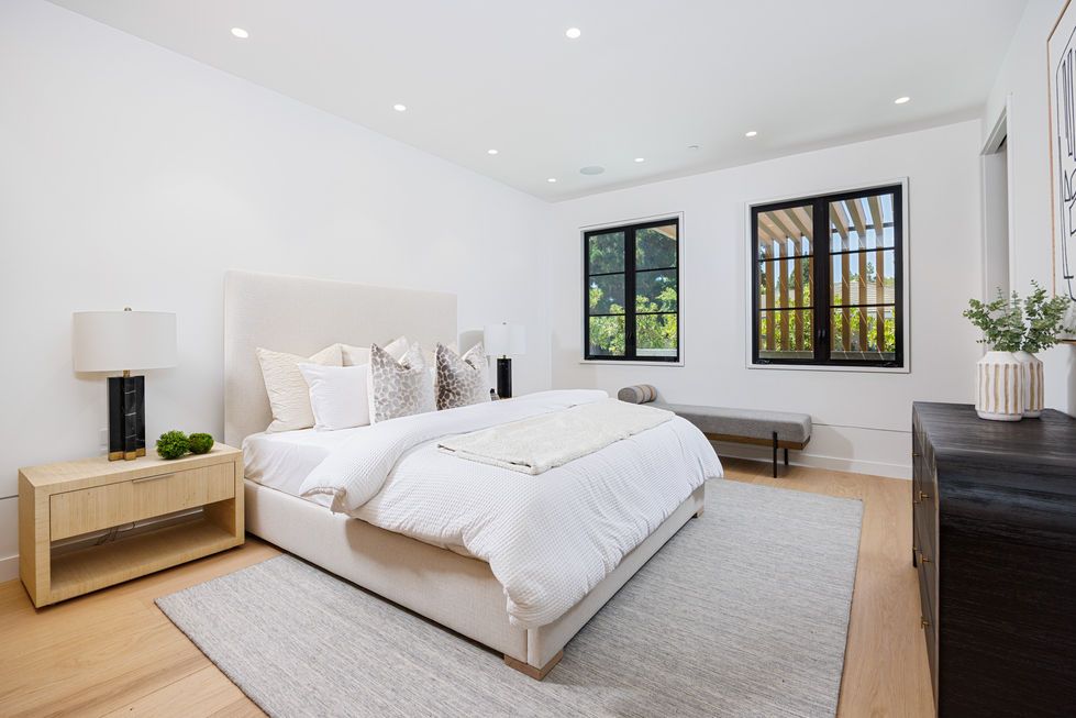 a bedroom with a large bed and two windows