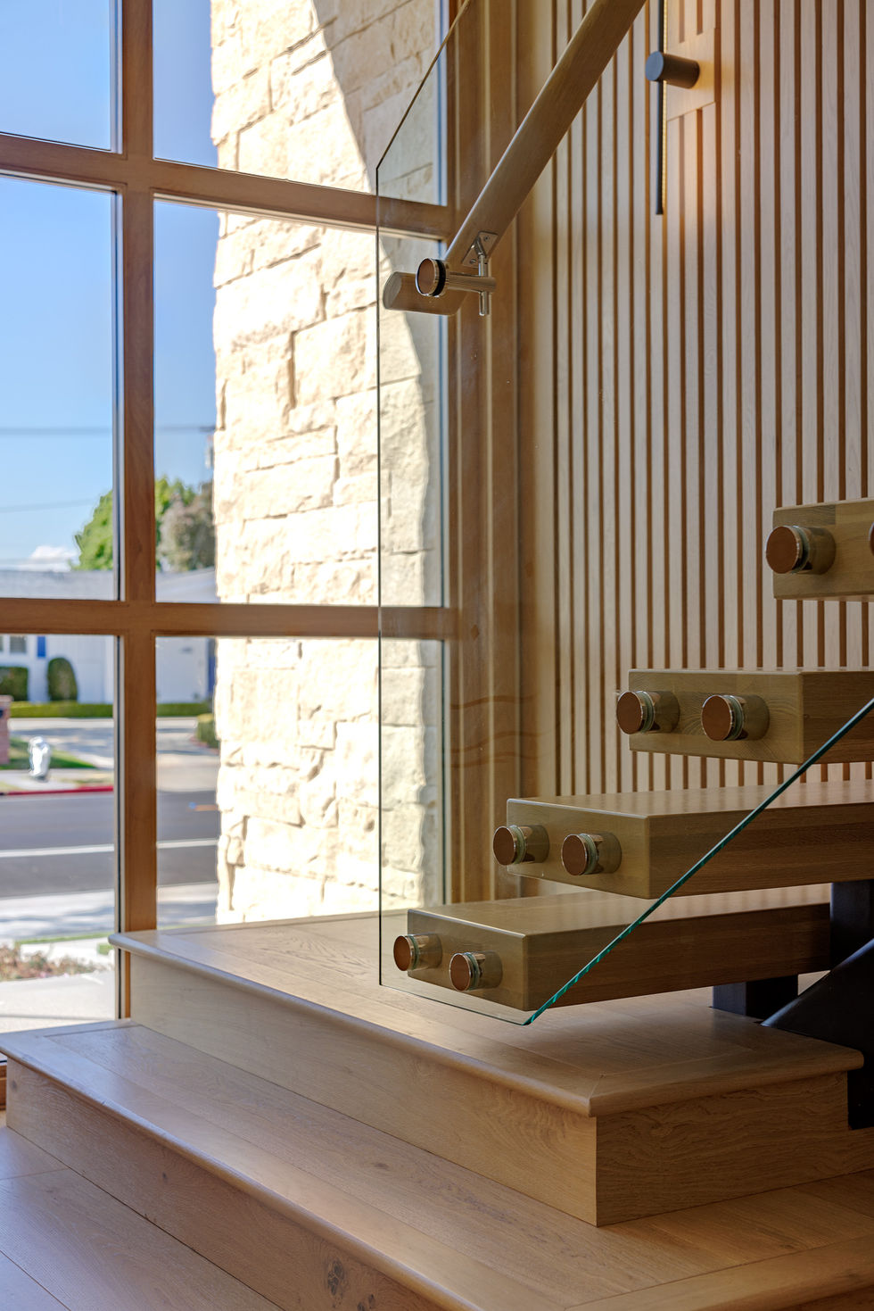 a wooden staircase with a glass railing and a window
