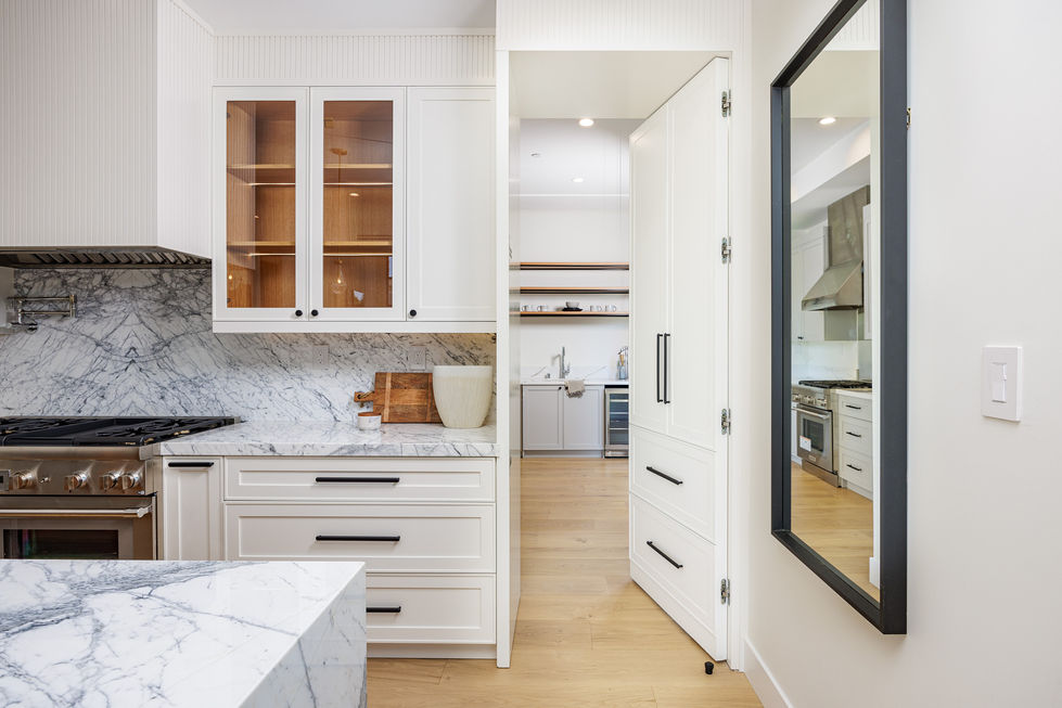 a kitchen with white cabinets and marble counter tops