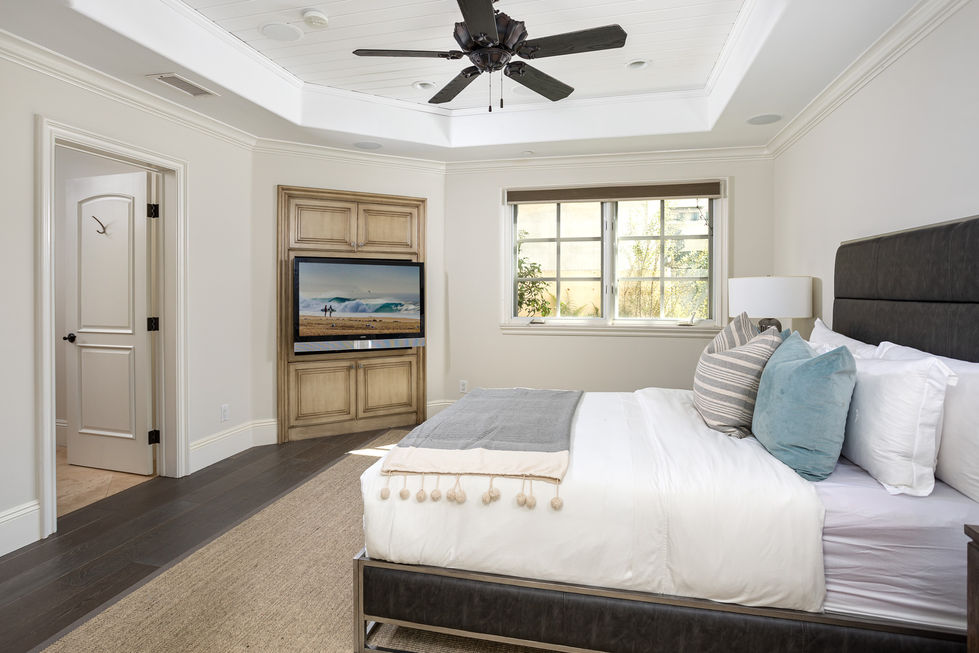 a bedroom with a ceiling fan and a flat screen tv